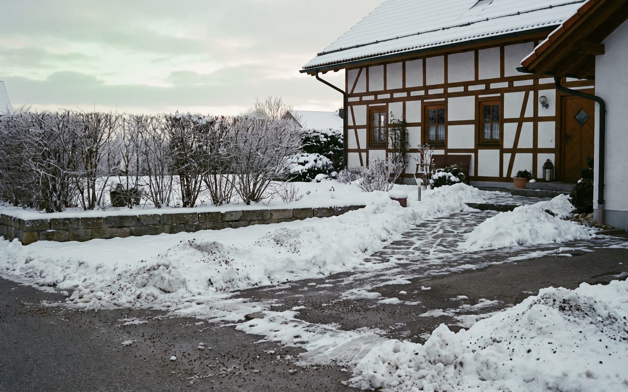 Geräumter und gestreuter Gehweg vor einem Wohnhaus an einem Wintermorgen